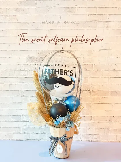 For the secret self-care philosopher, this hamper is a perfect fit. It features a "Happy Father's Day" balloon and a rustic floral arrangement in a wooden bucket, creating a calm and earthy vibe.
