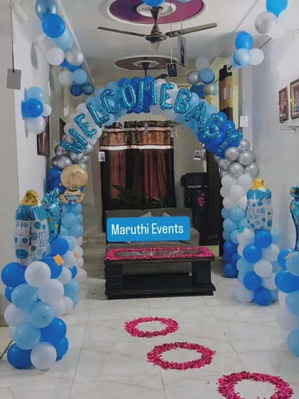 A 'Welcome Baby' entrance decoration with a blue, white, and silver balloon arch and a pathway of rose petals.