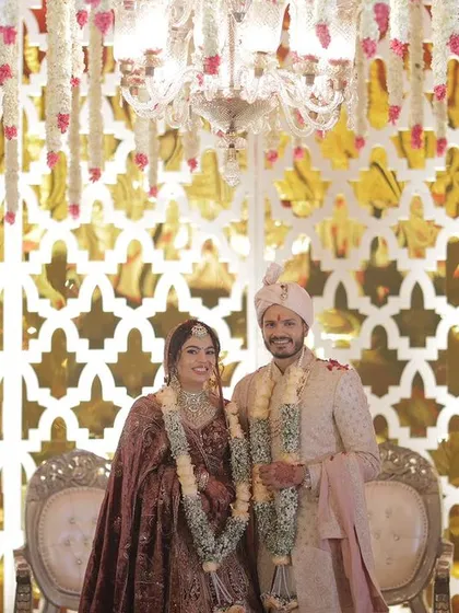 The stage for the wedding ceremony is just as important as the mandap. This setup features a gleaming gold lattice backdrop and traditional chairs, creating a regal setting for the couple.