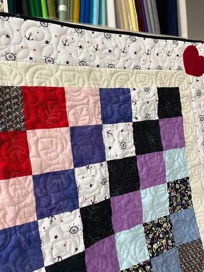 A patchwork baby quilt with a nautical theme, featuring anchor and steering wheel prints.