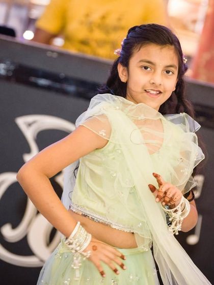 A close-up of the young girl in her mint green Mehendi outfit, showing her playful pose and the delicate details of the dress.