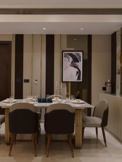 A symphony of modern elegance and understated luxury, this dining space boasts sleek marble finishes, rich wooden accents, and gilded highlights. Perfectly complemented by abstract art and refined decor, it exudes sophistication and timeless charm.