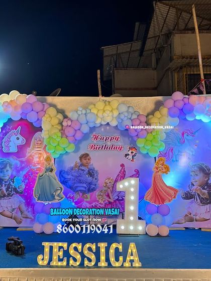 A magical unicorn and princess theme for Jessica's first birthday. This large outdoor setup features a custom photo backdrop and a pastel rainbow balloon arch.