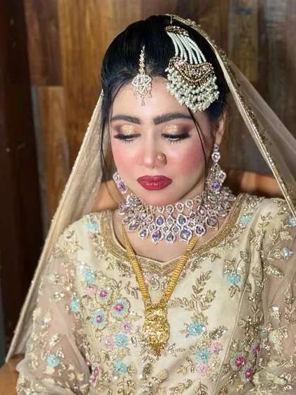 This Walima bride looks absolutely radiant. Her makeup features a soft gold eyeshadow, a classic red lip, and a glowing base that enhances her natural beauty.
