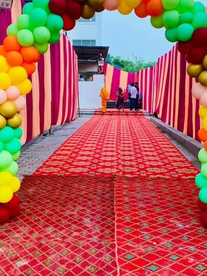 A long walkway decorated for a jungle-themed party, with a colorful balloon arch and tent-style draping creating an adventurous entrance.