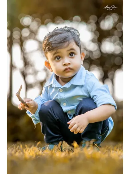 Crouching down to get a closer look at the world. This low-angle shot of Ivaan holding a small stick captures the inquisitive nature of a toddler exploring his surroundings.