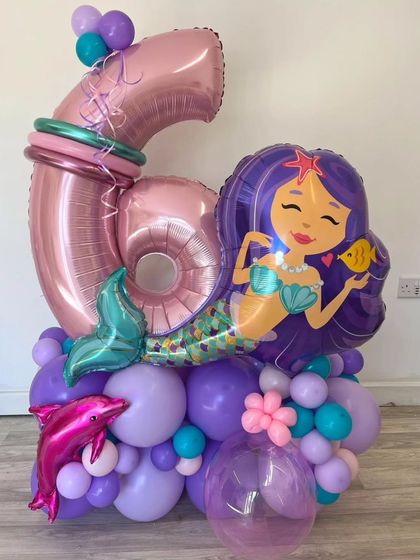 A mermaid-themed balloon bouquet for a 6th birthday, complete with a large mermaid foil balloon and a dolphin accent.