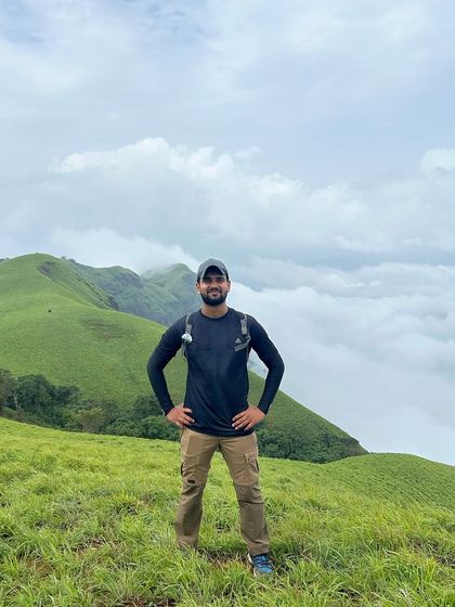 A trekker stands proudly above a sea of clouds on the Bandaje trail. Reaching these heights offers a truly breathtaking perspective.