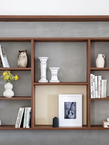 In this compact living area, we carved niches behind the sofa to create a bookshelf and curio display, making optimal use of the space.