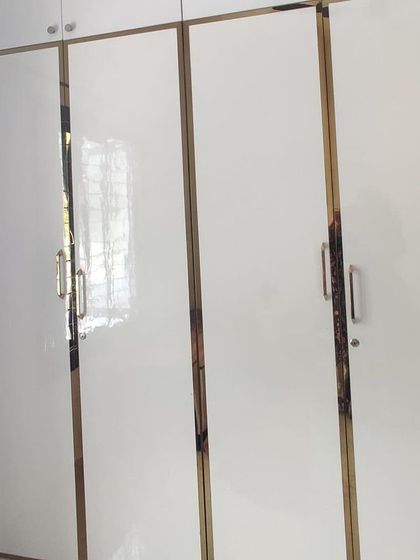 A simple yet elegant white wardrobe with gold-trimmed handles, part of a housewarming project.