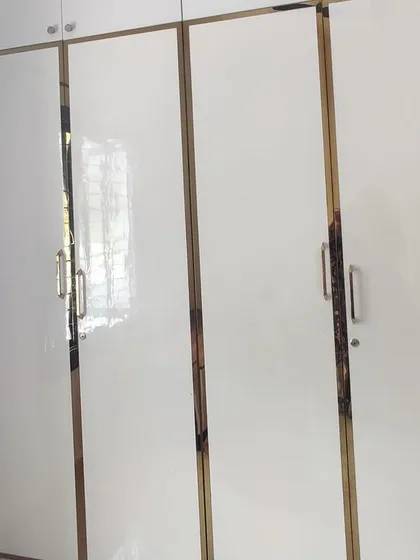 A simple yet elegant white wardrobe with gold-trimmed handles, part of a housewarming project.
