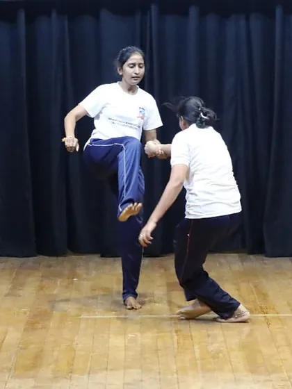 The confidence gained from our training is evident when participants showcase their skills. Here, a woman demonstrates a powerful knee strike defense, a culmination of the practical training received during our women's self-defense program.