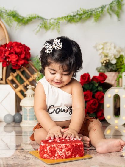 This little cowgirl is getting right into her red velvet cake. Our cake smash sessions are all about letting kids be kids and enjoying every messy second.