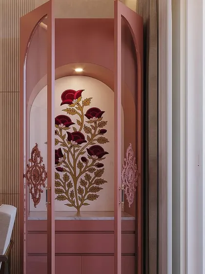 A closer look at the pink pooja unit with its doors open, revealing the built-in lighting that highlights the beautiful floral artwork inside. This piece is a testament to custom craftsmanship.