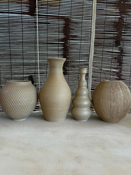 A collection of large, unglazed vases in various shapes and sizes. Each one is thrown on the wheel and showcases a different form, from classic curves to textured surfaces.