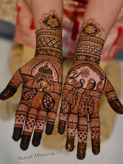A close-up of a detailed bridal mehendi. One hand features a doli (palanquin) scene, while the other showcases a pair of peacocks, both classic symbols in Indian wedding art.