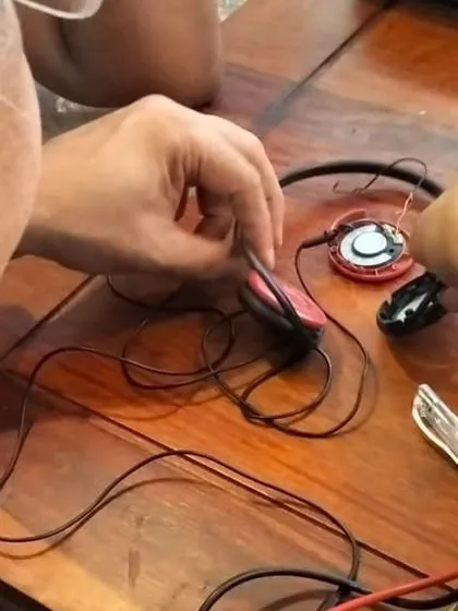A close up of a mentor's hands carefully repairing a set of headphones. This image highlights the precision and patience required for delicate electronic repairs.