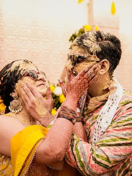 A playful Haldi moment between the bride and groom. These are the fun, messy, and memorable interactions that make for great candid wedding photography.