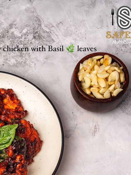 A close up of the Crispy Chicken with Basil Leaves, showing the texture of the chicken and the fresh basil. It's served with a side of chopped garlic for extra flavour.