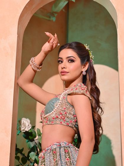 A portrait of the bride with her hair in a high, wavy ponytail, a variation of the half-updo. This style keeps the hair off her face while still showing off its length and volume.