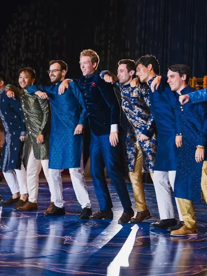 The groom and his groomsmen, a mix of friends from different backgrounds, all dressed in traditional Indian wear for their group performance. I love seeing this kind of energy and camaraderie on stage.
