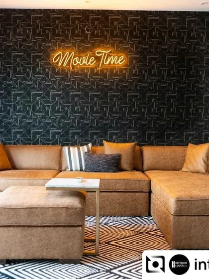 Movie night, anyone? I designed this dedicated home theater room with a large, comfortable sectional sofa and a dark, patterned wallpaper to create an immersive cinematic experience right at home. The neon sign adds a fun, playful touch.