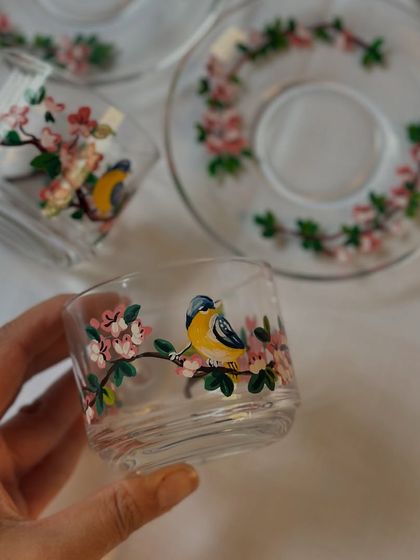 Holding one of the cherry blossom and bird tea glasses. You can really see the fine details and brushstrokes that go into each piece.