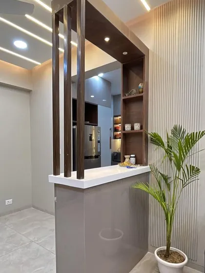 We designed this partition with a breakfast counter to elegantly separate the living and kitchen areas. The fluted wall paneling behind adds texture to the space.