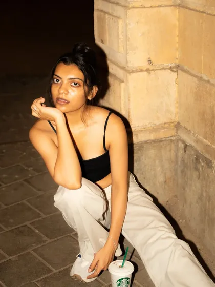 A casual, crouched pose on the pavement. This adds an urban, street-style authenticity to the night shoot.