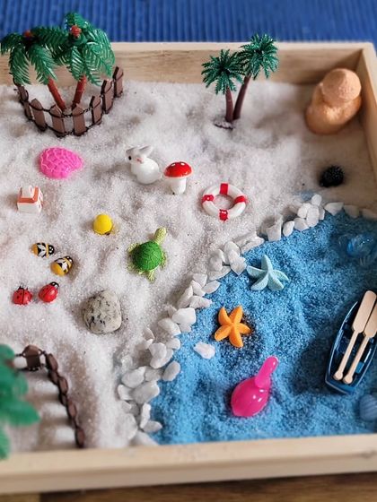 A whimsical beach scene created by a young participant. The process of arranging the sand, stones, and miniatures is a calming, meditative practice that helps children focus their minds.