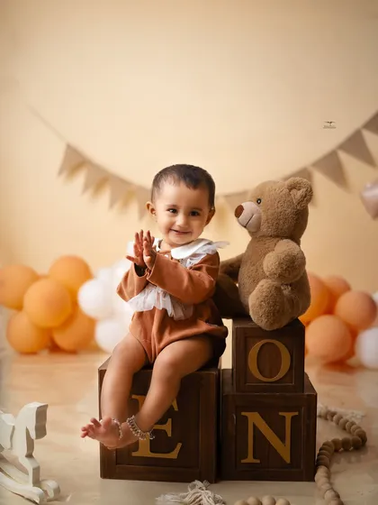 Clapping with joy for her first birthday. This portrait captures the happy energy of a milestone celebration, surrounded by balloons and her favorite teddy bear.