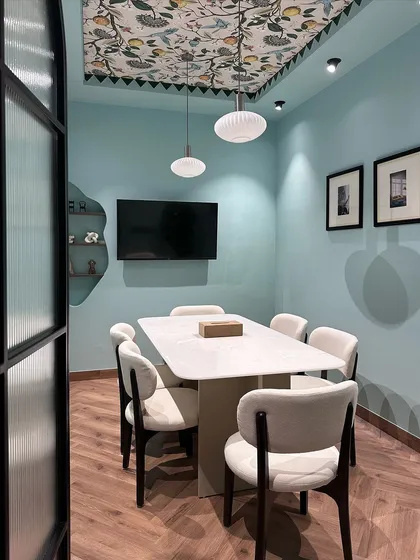 This is the main conference room in my studio. I used a serene blue on the walls and a custom-printed wallpaper on the ceiling tray to make the room feel unique. The space is equipped for presentations and collaborative work sessions.