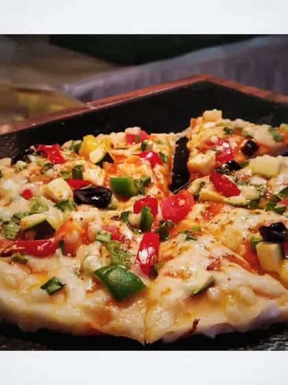 Home is where the pizza is. A close-up of a veggie-loaded pizza with a perfectly melted cheese topping, a crowd-pleaser at any event.