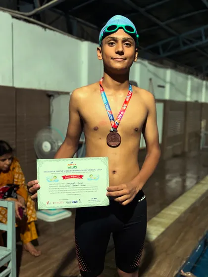 Ekampreet proudly displaying his medal and certificate after a successful competition. Every medal represents hours of practice and dedication in the pool.
