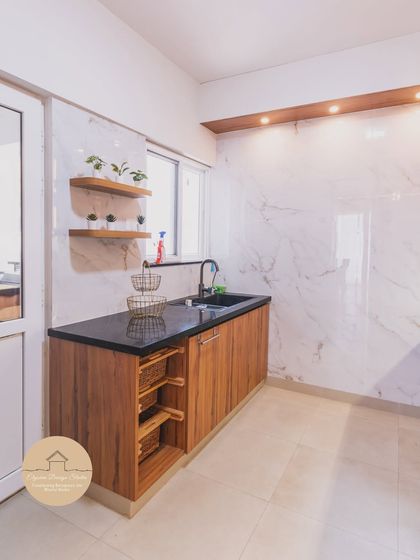 This utility area is designed to be as beautiful as the main kitchen. We used the same wood-finish cabinetry and marble-effect wall tiles, adding floating shelves for plants to create a bright and functional space for daily chores.
