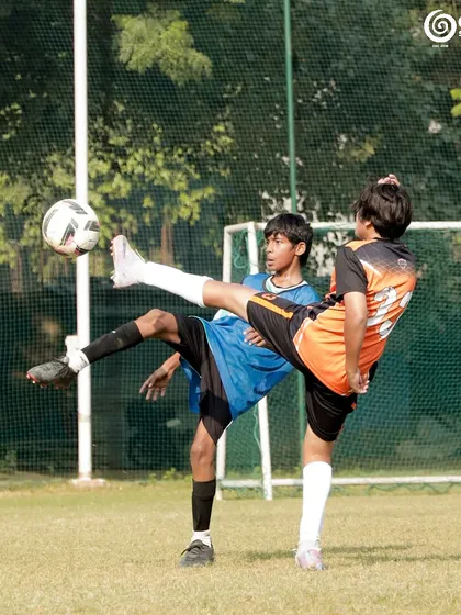 A spectacular high kick as two players contest for the ball in mid-air.