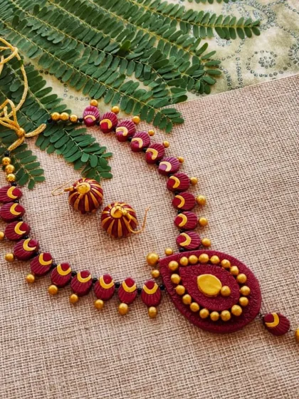 Another angle of the maroon and gold teardrop necklace, showing the full length of the piece.