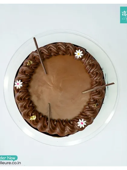 An overhead shot of our Chocolate Truffle Cake, showing the symmetry of the piping and the delicate gold leaf details.