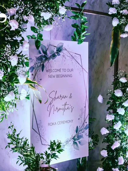 The custom welcome sign for a Roka ceremony, framed by an arch of fresh white flowers and greenery. This was the first beautiful detail guests saw as they arrived to celebrate the couple's new beginning.