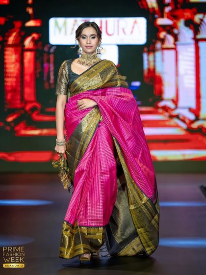 The flow and drape of the pink silk saree are highlighted as the model walks the runway, showcasing its luxurious texture.