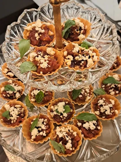 Here is a little taste of my gourmet side. These bite-sized tarts are filled with sweet caramelized onions and balsamic tomatoes, then topped with crumbled feta and fresh basil. They are an absolute treat for any party or gathering.