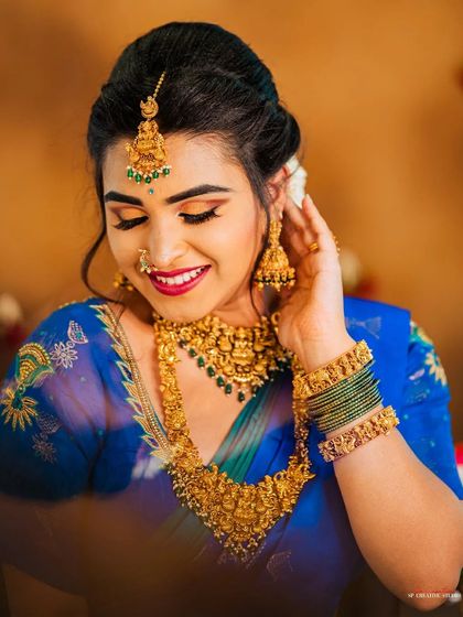 Another beautiful close-up from the blue saree series, this time capturing a candid moment. This shot is perfect for showcasing bridal makeup and the intricate craftsmanship of the gold temple jewelry.