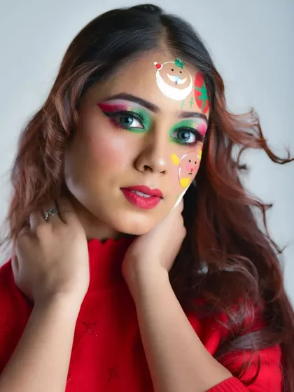 A fun and festive Christmas makeup look. This combines glamorous green and pink eyeshadow with playful, hand-painted face art of Santa, a snowman, and a reindeer for a unique holiday style.