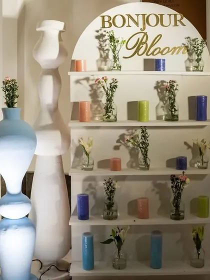 The 'Bonjour Bloom' corner, a modern take on a flower display with clean white shelves, minimalist vases, and colorful candles.