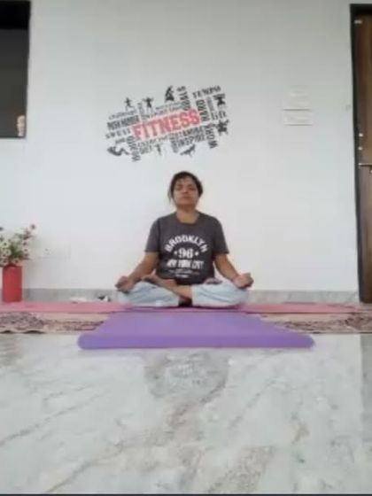 An instructor sits in Sukhasana (Easy Pose) at the end of an online session, creating a moment of shared stillness. Our classes always include time for centering and reflection.