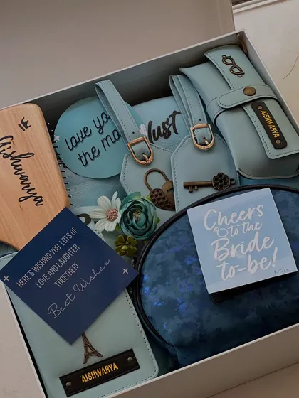 A beautiful blue-themed hamper for the bride-to-be. This box is filled with personalized travel essentials like a passport holder and luggage tags, a custom hairbrush, and a makeup pouch.