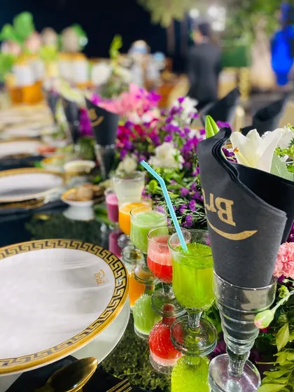 A close-up of the table setting, featuring custom "Brite" branded napkins, Versace-style plates, and colorful welcome drinks.
