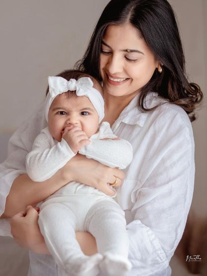 A close-up of a mother holding her baby, who is looking at the camera with a sweet, curious expression.