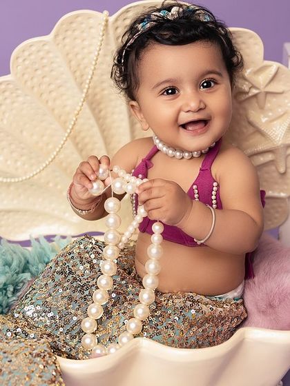 Pearls and giggles from the sweetest little mermaid. The details in this under-the-sea setup, from the sparkling tail to the pearl necklace, create a truly magical ocean scene.