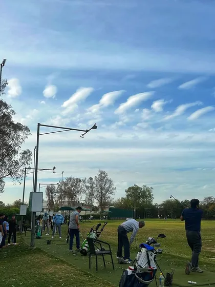 The clouds create a stunning pattern in the sky above a packed driving range.